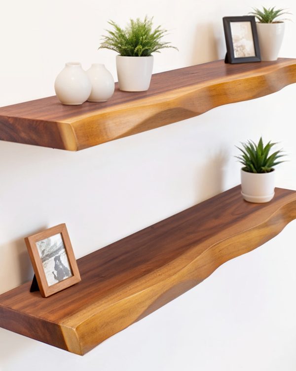 Two long live edge shelves on a white bedroom wall holding plants, ceramics and framed photos